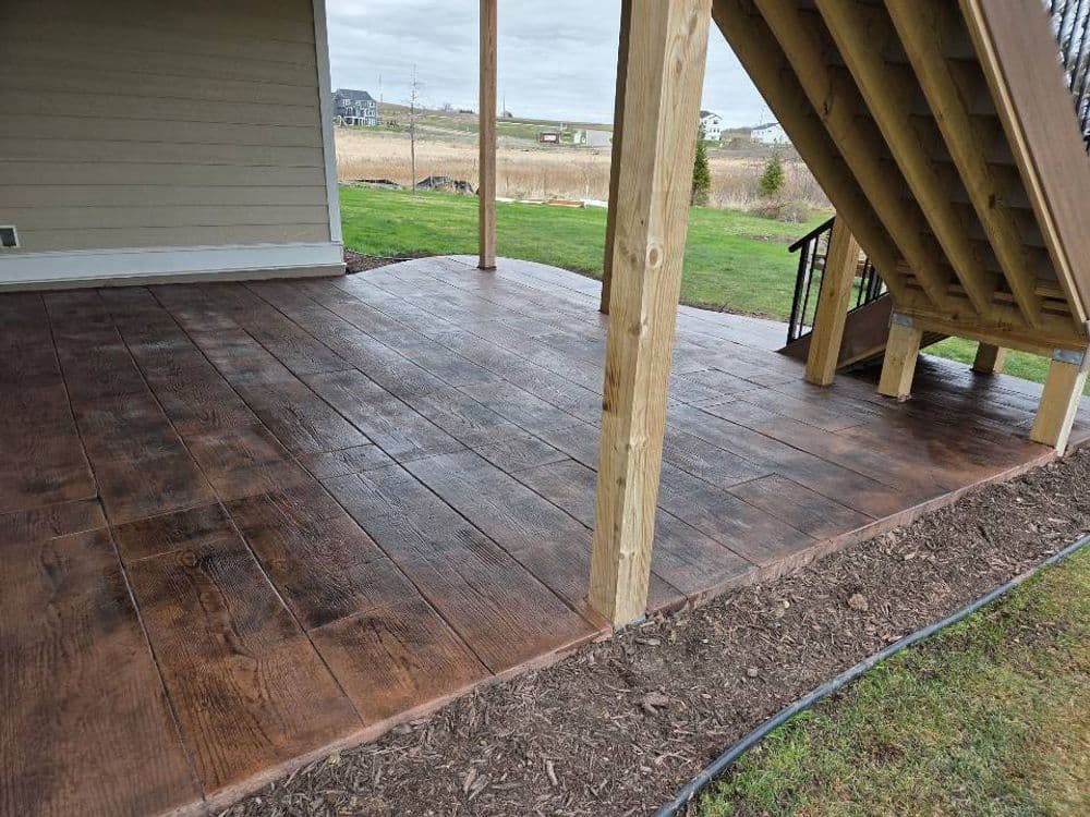 Stained wooden deck under stairs with landscaping, enhancing outdoor living space.