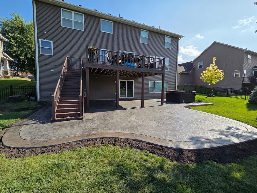 Two-story house with a back deck, landscaped yard, and a newly stamped concrete patio.