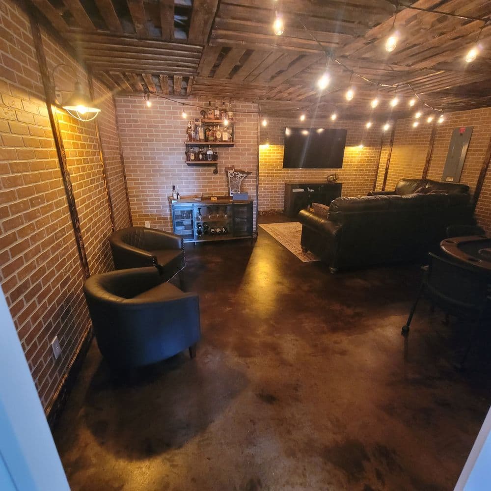 Cozy basement lounge with exposed brick walls, a bar, a TV, and ambient string lights.